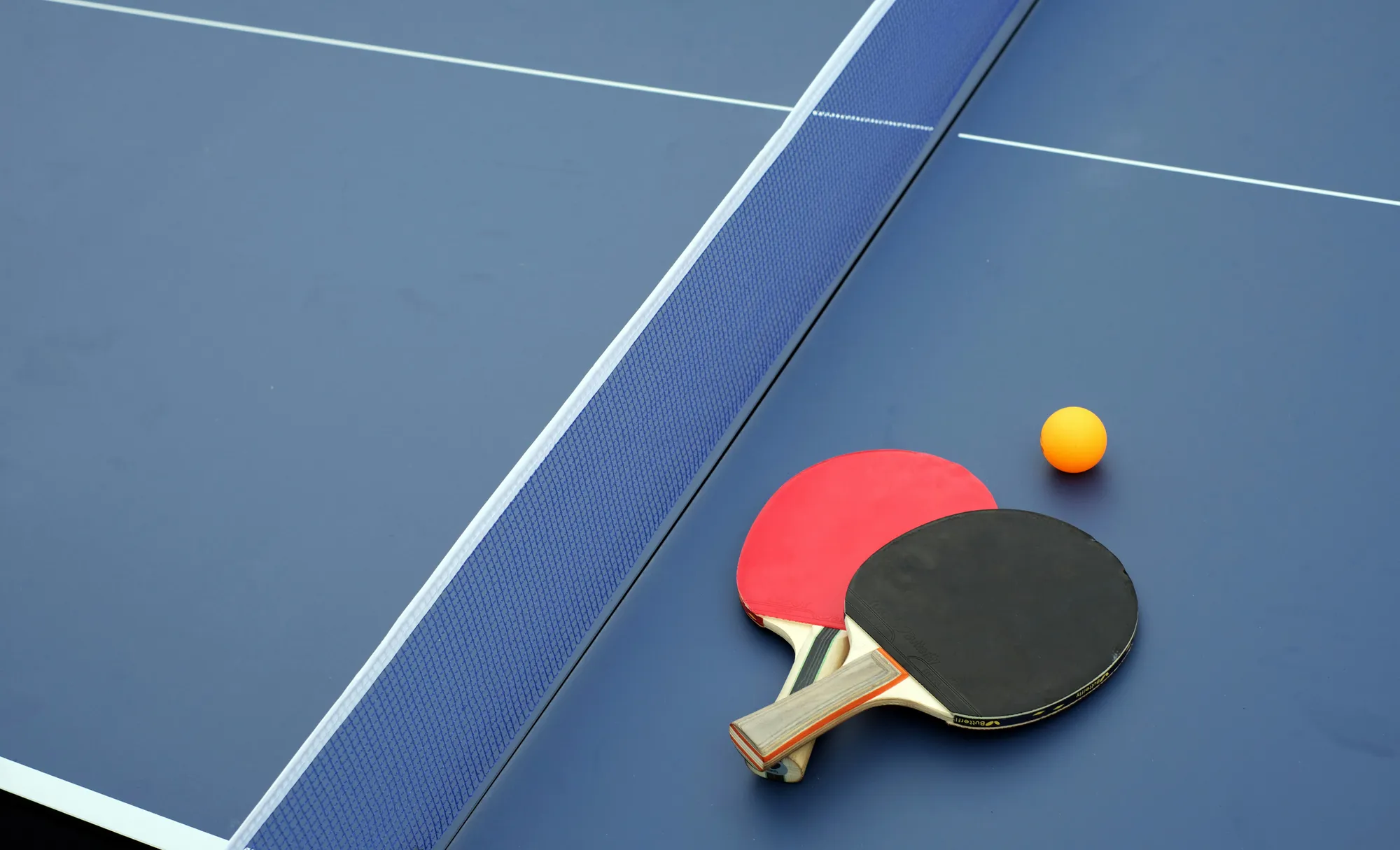 Ping pong paddles and ball on a blue table